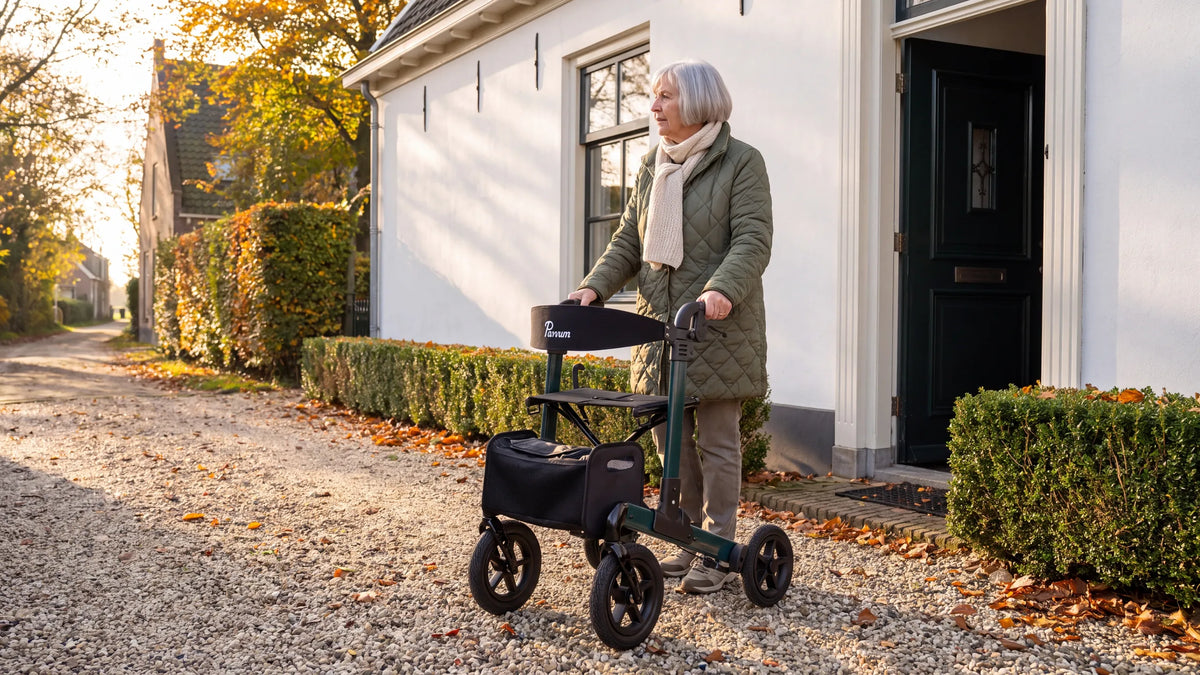 Parvum Luxo Air in petrol green on a gravel path in front of a white house; a woman stops for a moment and looks at the road.