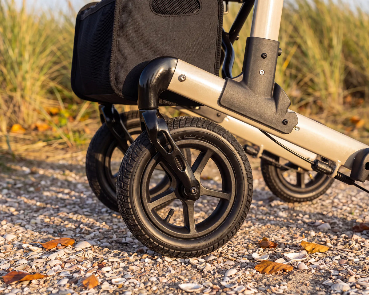 Close-up of the air tire and front wheel of the Parvum Luxo Air in champagne on a shell path.